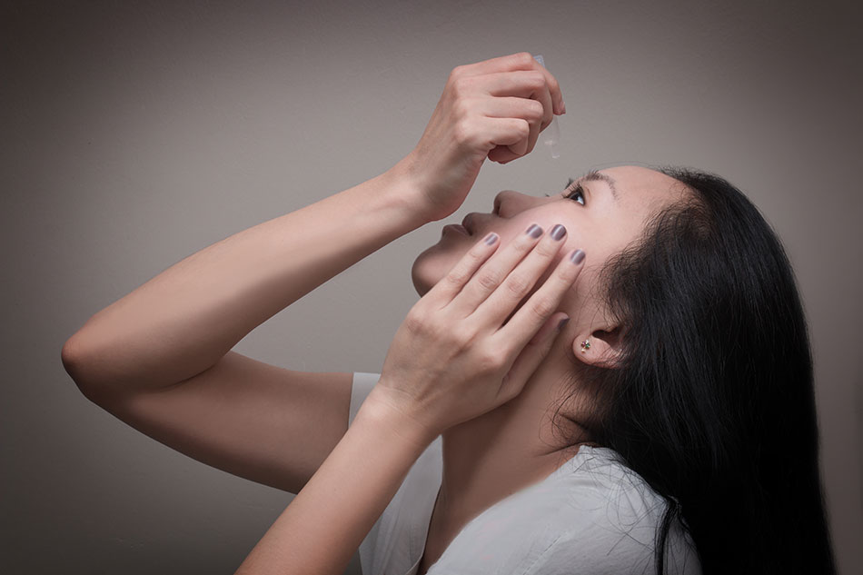 Woman applying eye drops