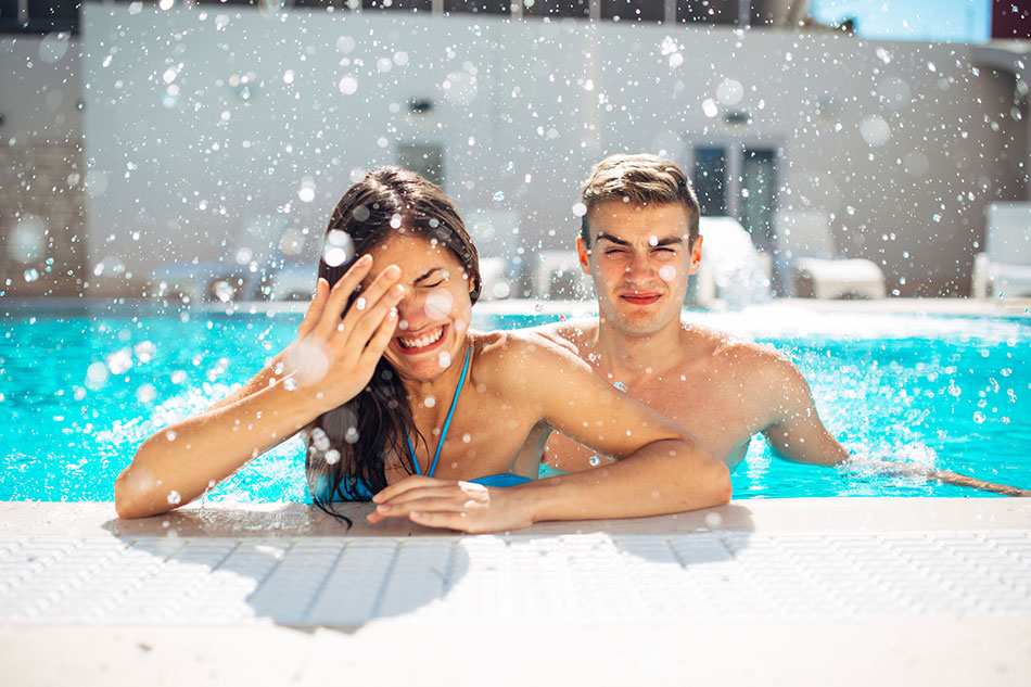 Young woman with eye problem in pool and concerned male friend